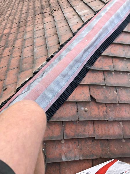 Dry ridge roll with pleated black edges laid over the red plain tiles