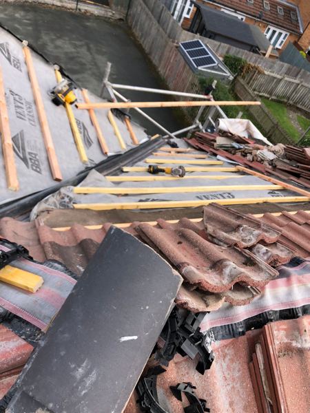 Stripped slope on new membrane and battens, old tiles stacked alongside