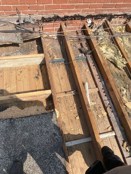 Bare joists at the house wall where the old felt had failed