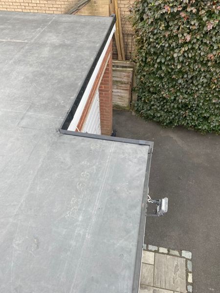 Finished rubber roof with black edge trims above the garage door
