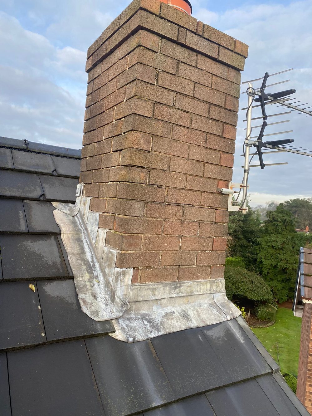 New lead at the foot of a stack &mdash; a front apron across the downhill face and a stepped side flashing chased into the brickwork