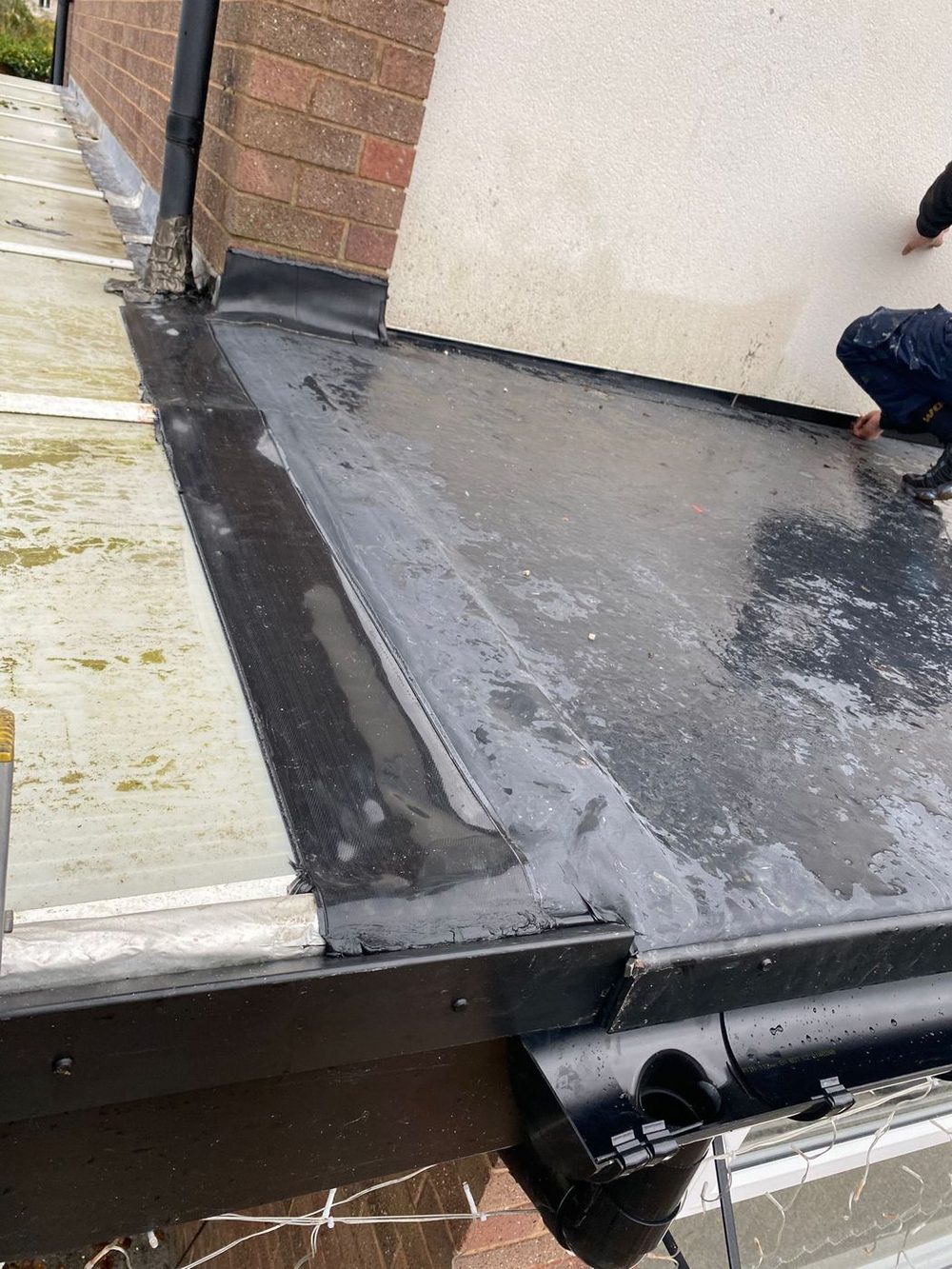 EPDM dressed down into a new gutter, with the edge trim and downpipe in place