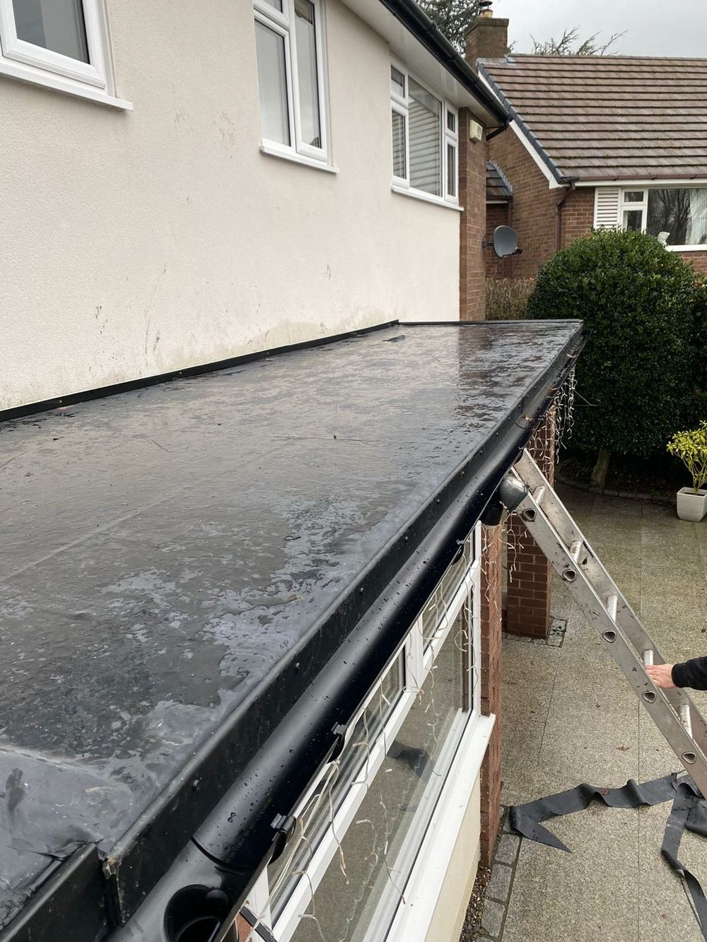 A finished flat roof seen from the top of the ladder, the trim line running straight along the front gutter